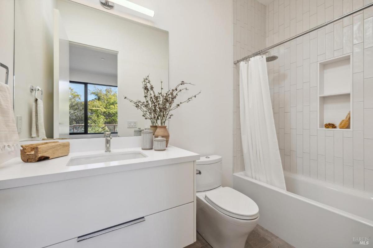 A bathroom with a single sink, a toilet, and a tiled wall.