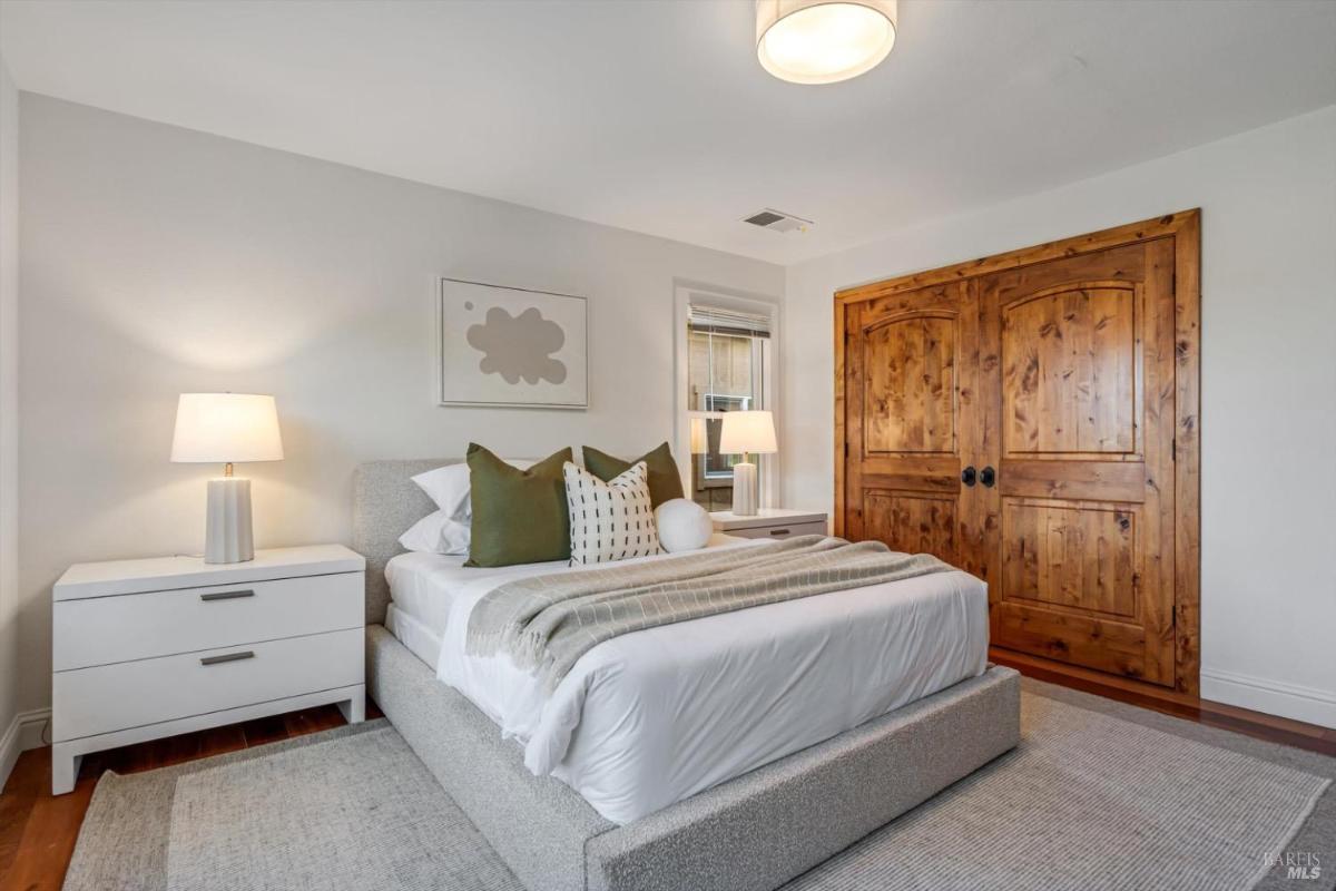 Bedroom with a bed, nightstands, and a double-door wooden closet.