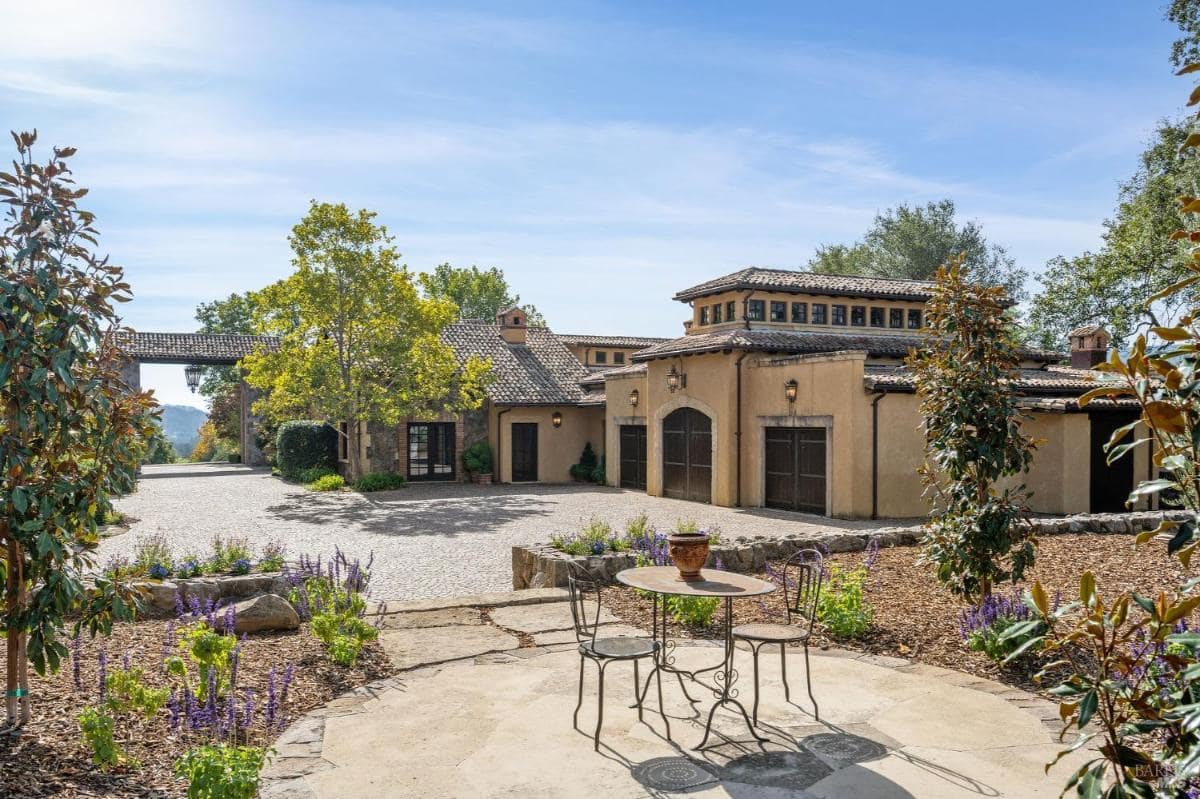 A courtyard with a cobblestone driveway and garage doors.