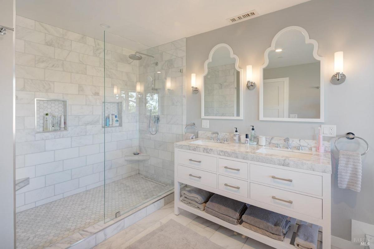 A modern bathroom featuring a glass shower, double sinks, and marble countertops.