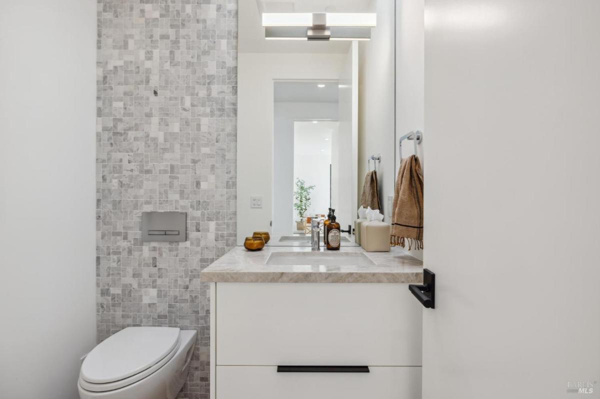 A bathroom with a single sink, a toilet, and a tiled wall.