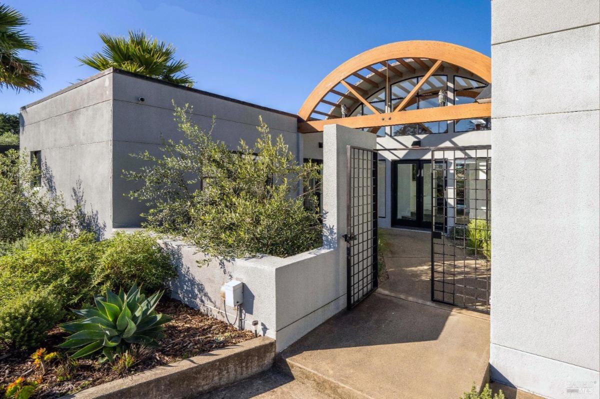 An entrance gate leading to a contemporary building surrounded by landscaping.