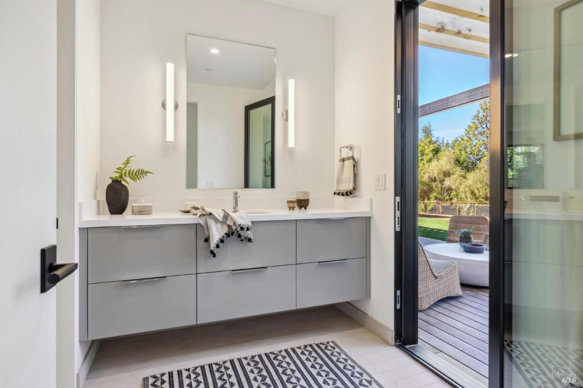 A bathroom with a gray vanity and outdoor access.
