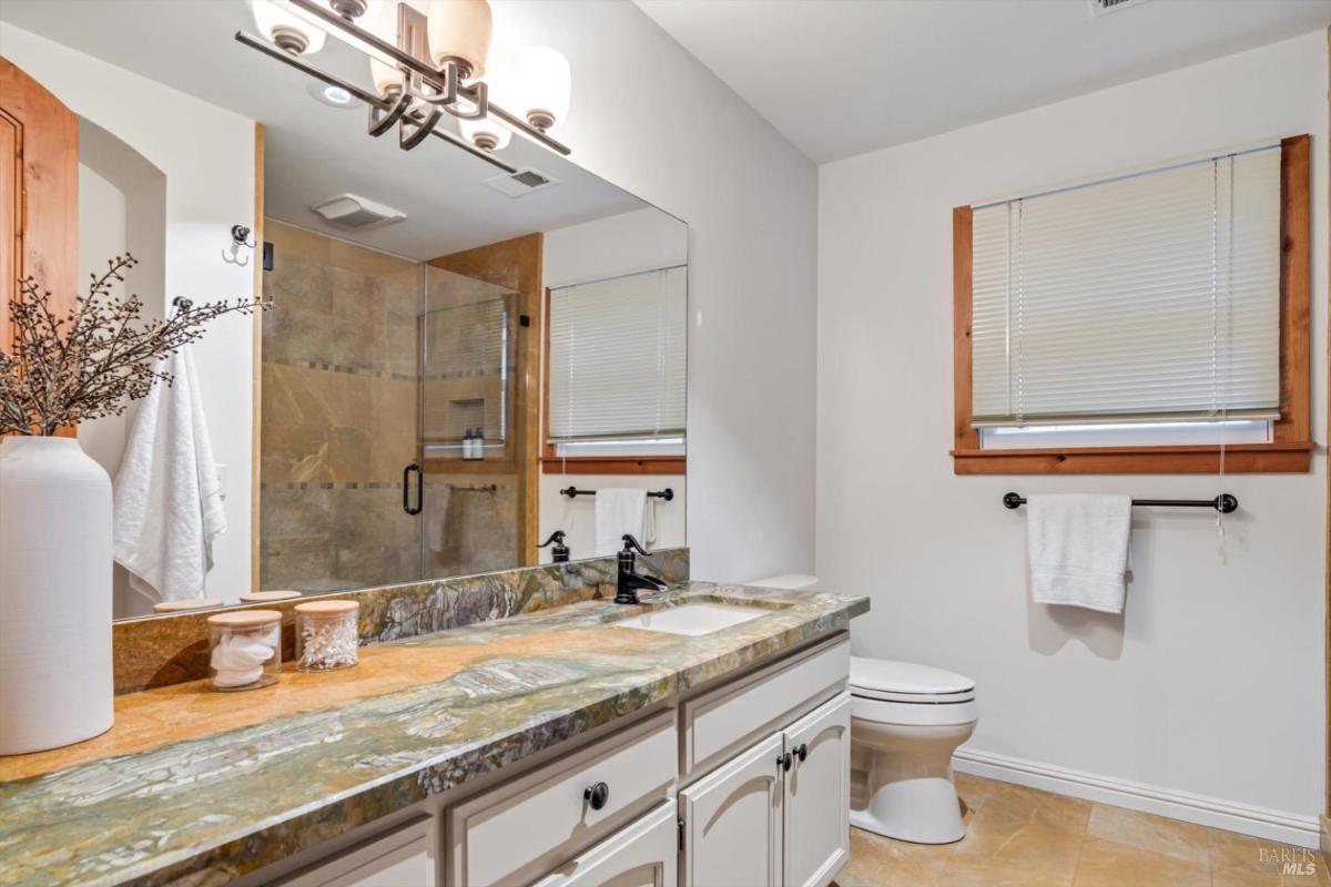 Bathroom with a single sink, a mirror, and a glass-enclosed shower.