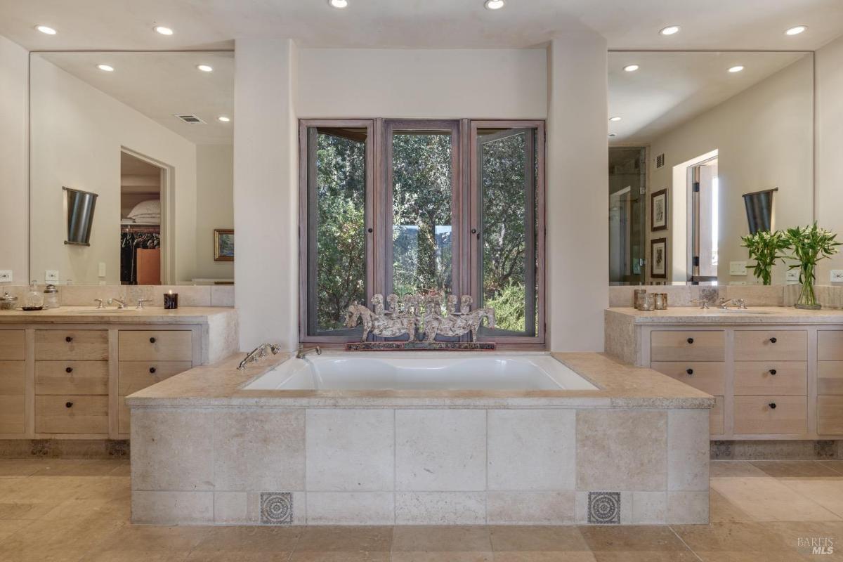 Bathroom with a central bathtub, large mirrors, and dual vanities.