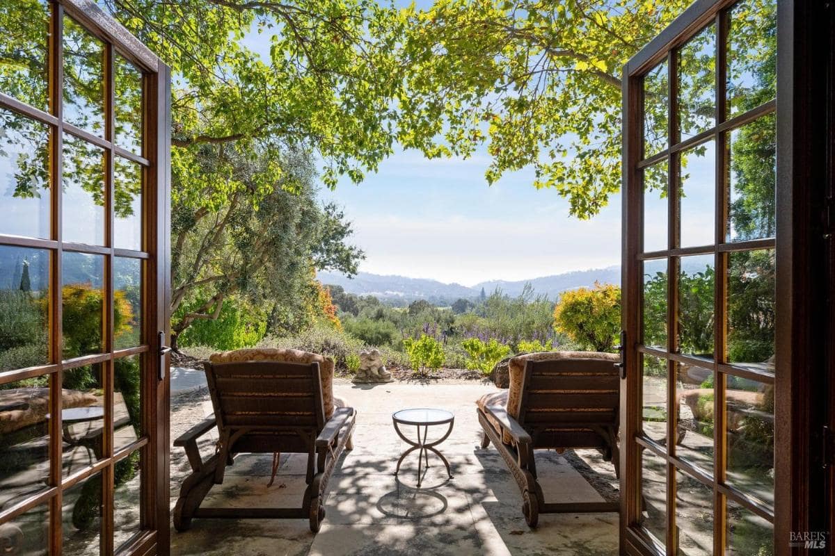 A patio with two lounge chairs and a view of the garden.