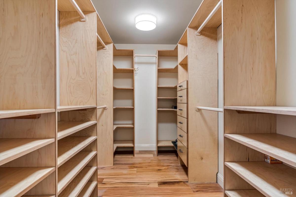 Walk-in closet with multiple shelves, drawers, and hanging rods