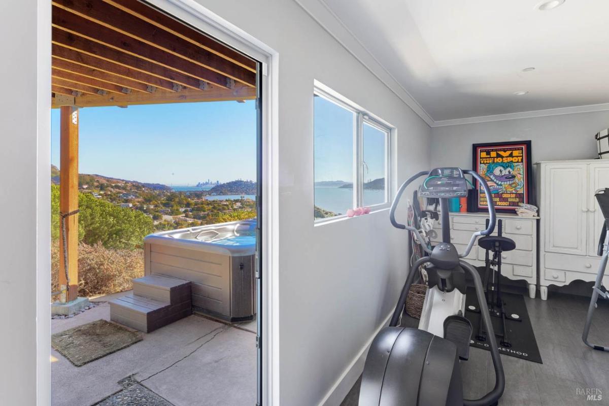 A home gym with exercise equipment and a view of the outdoors, featuring large windows that offer a glimpse of the landscape outside.