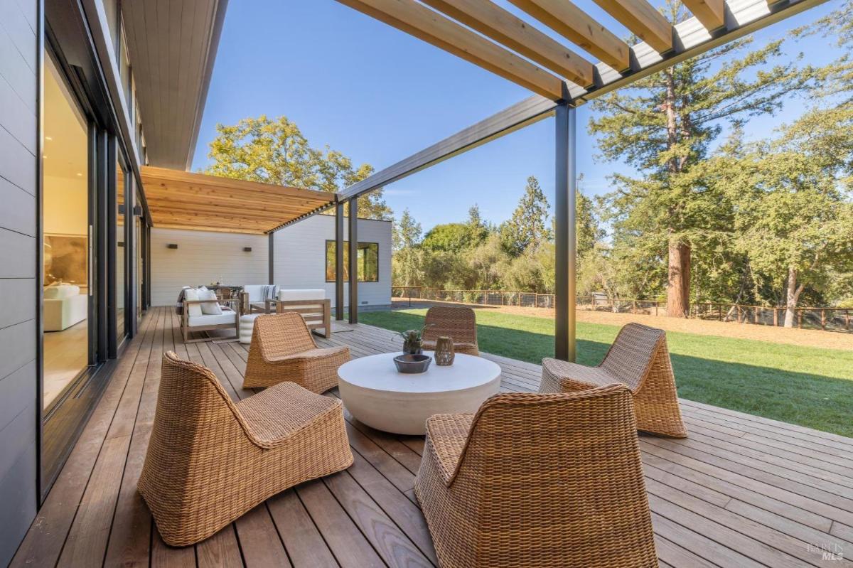 A wooden deck with outdoor seating and a pergola.