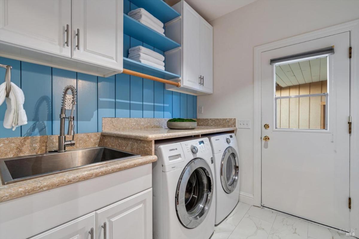 Laundry room with a washer, dryer, sink, and storage cabinets.