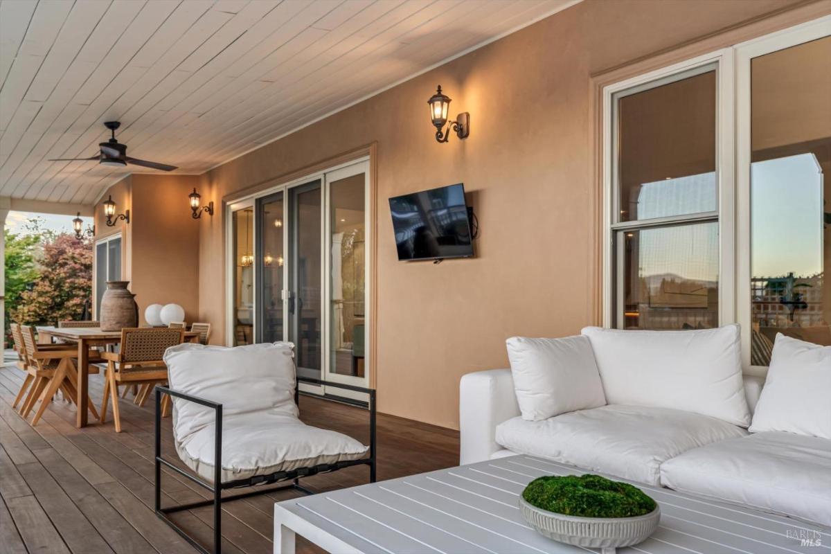Outdoor patio with seating, a dining table, and a wall-mounted television