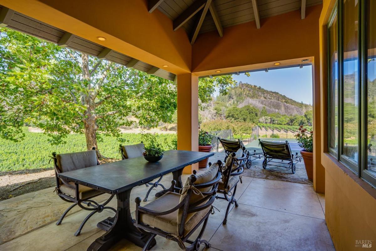 Covered patio with a dining table and views of the surrounding landscape.