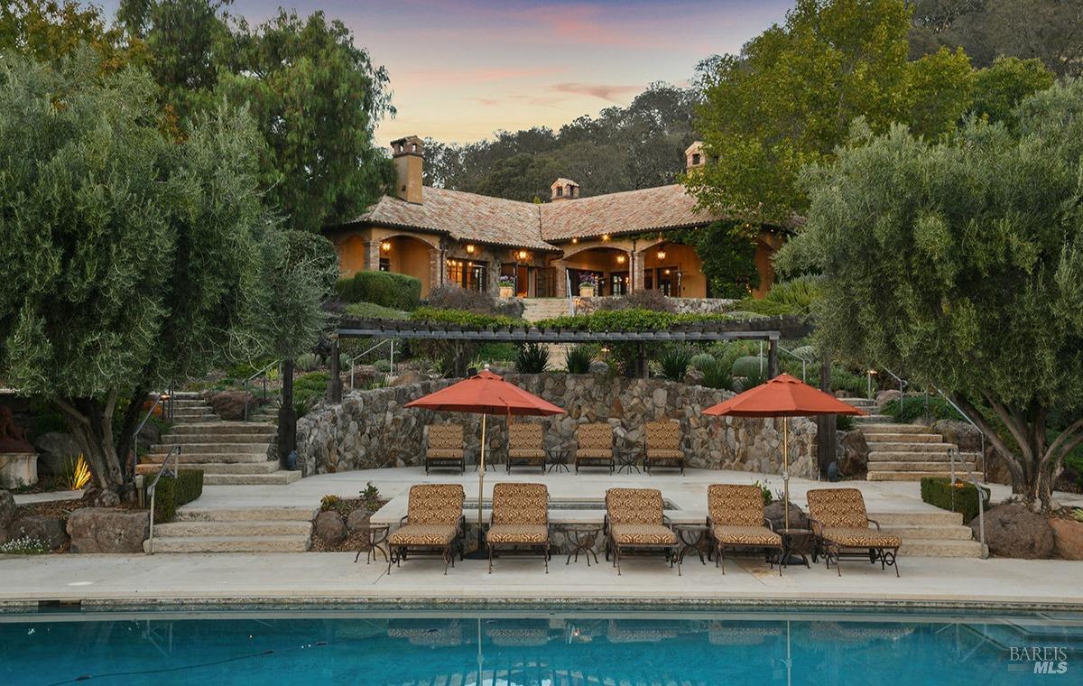 A house view from the pool with stone steps and greenery.