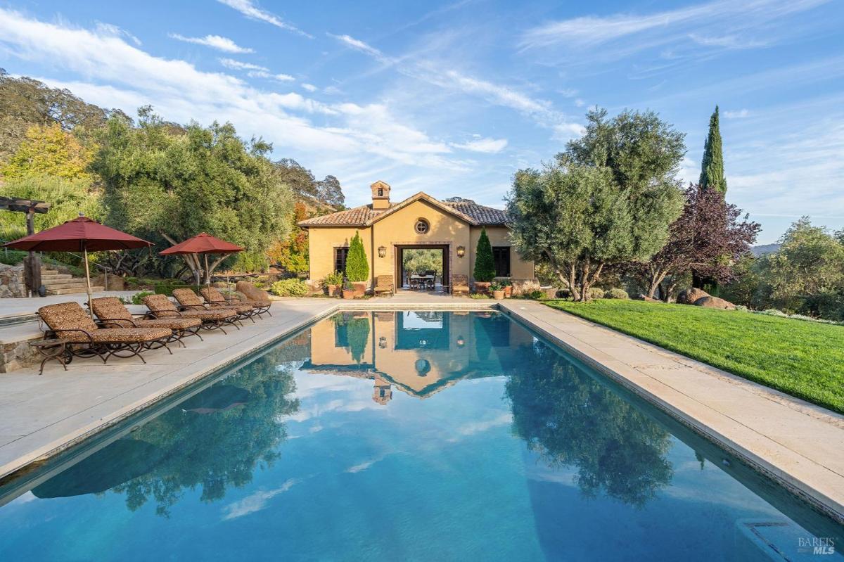 A pool house with large open doors reflecting in the pool.
