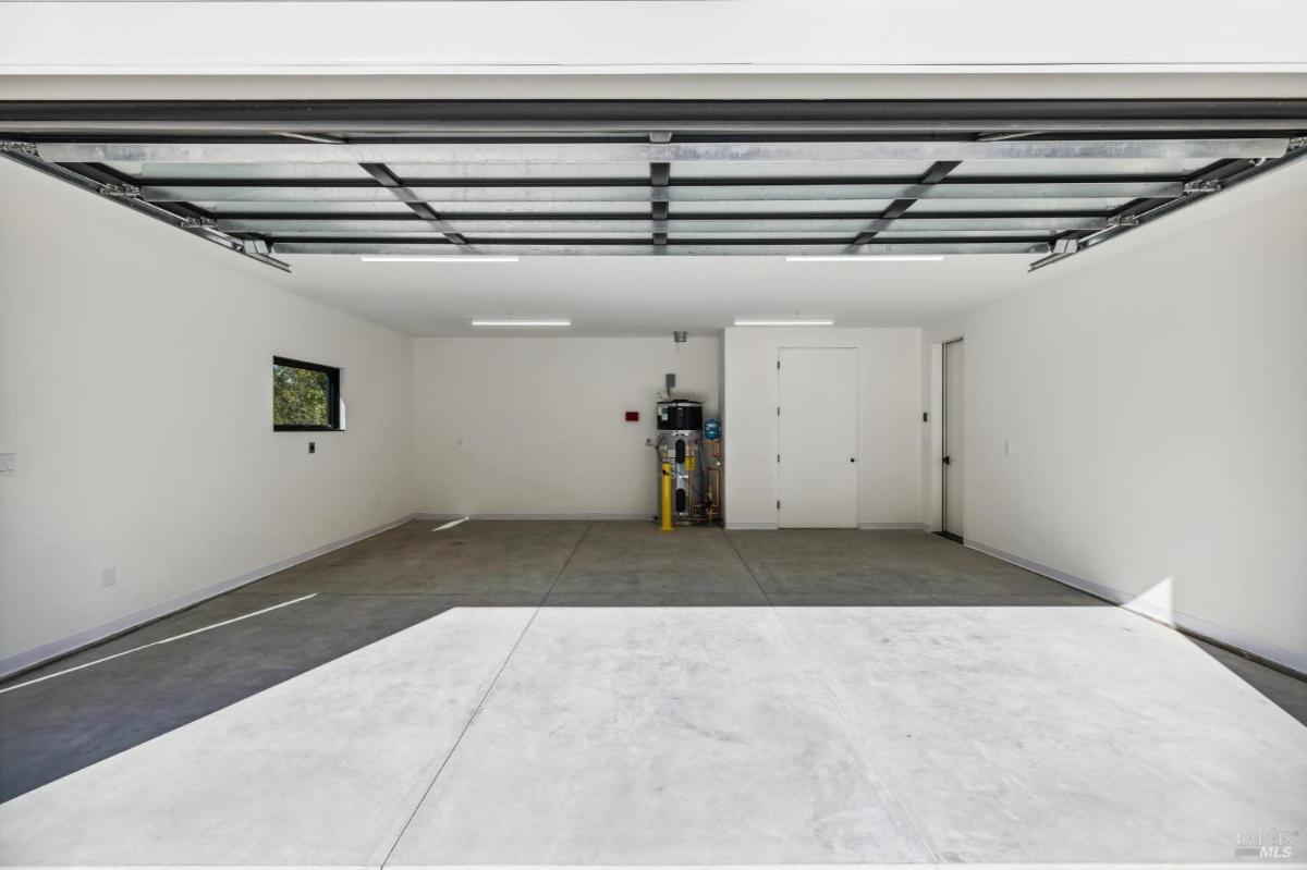 Empty two-car garage with white walls and concrete flooring.