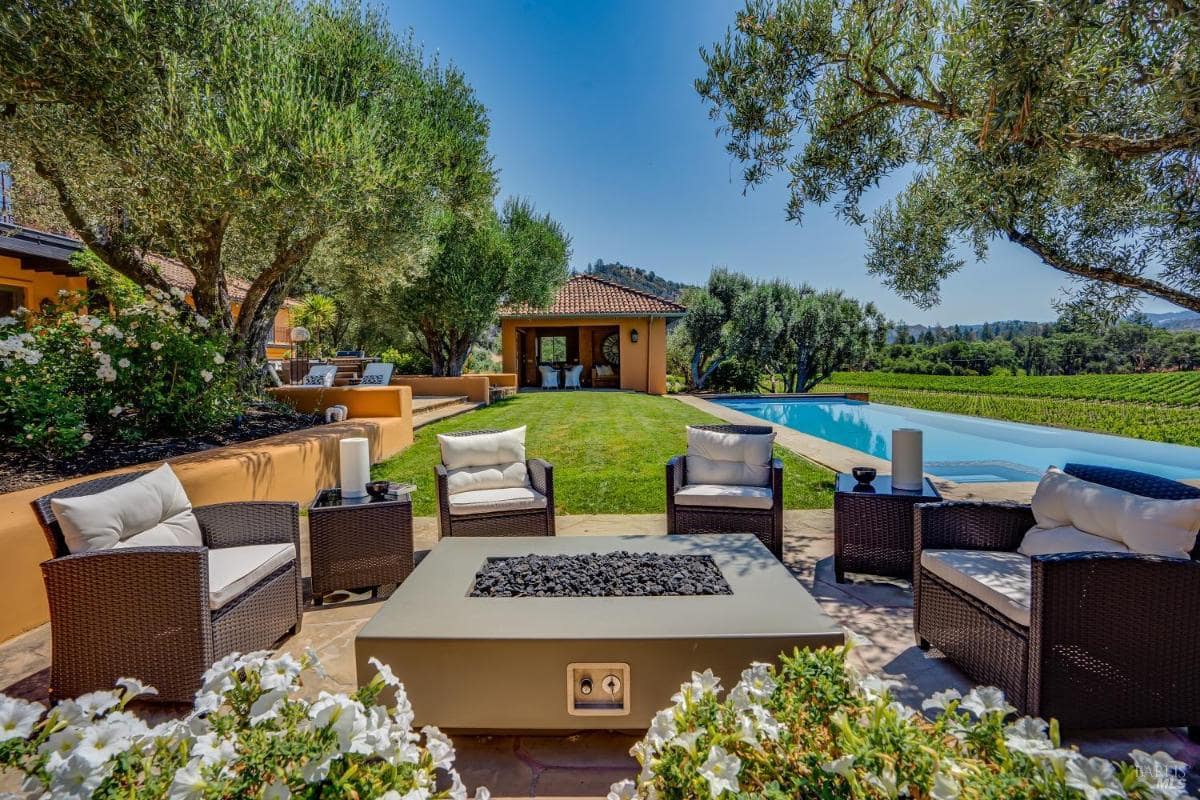 Poolside seating area with lounge chairs and a grassy lawn.