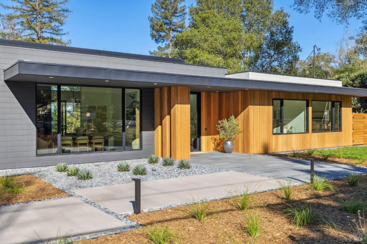 Front of a modern home with wood paneling and large windows.