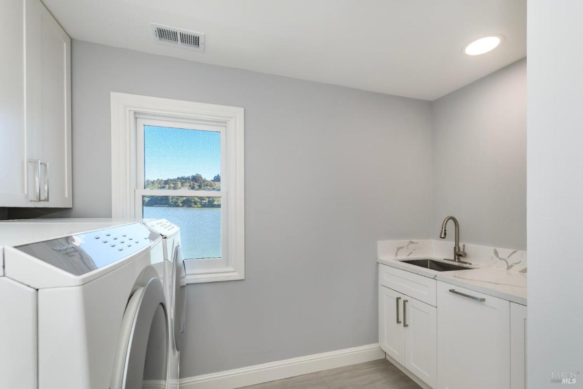 Laundry room with a washer, dryer, and sink next to a window.