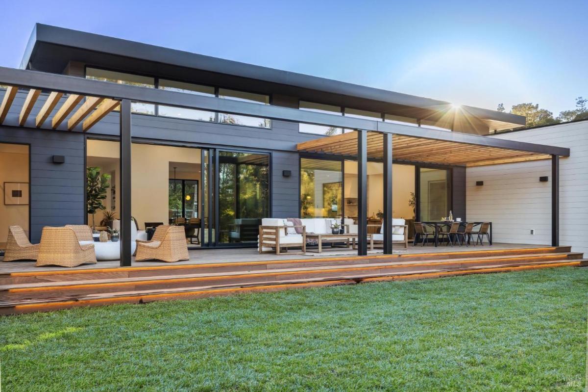 Backside of the house with a large deck, pergola, and lawn.