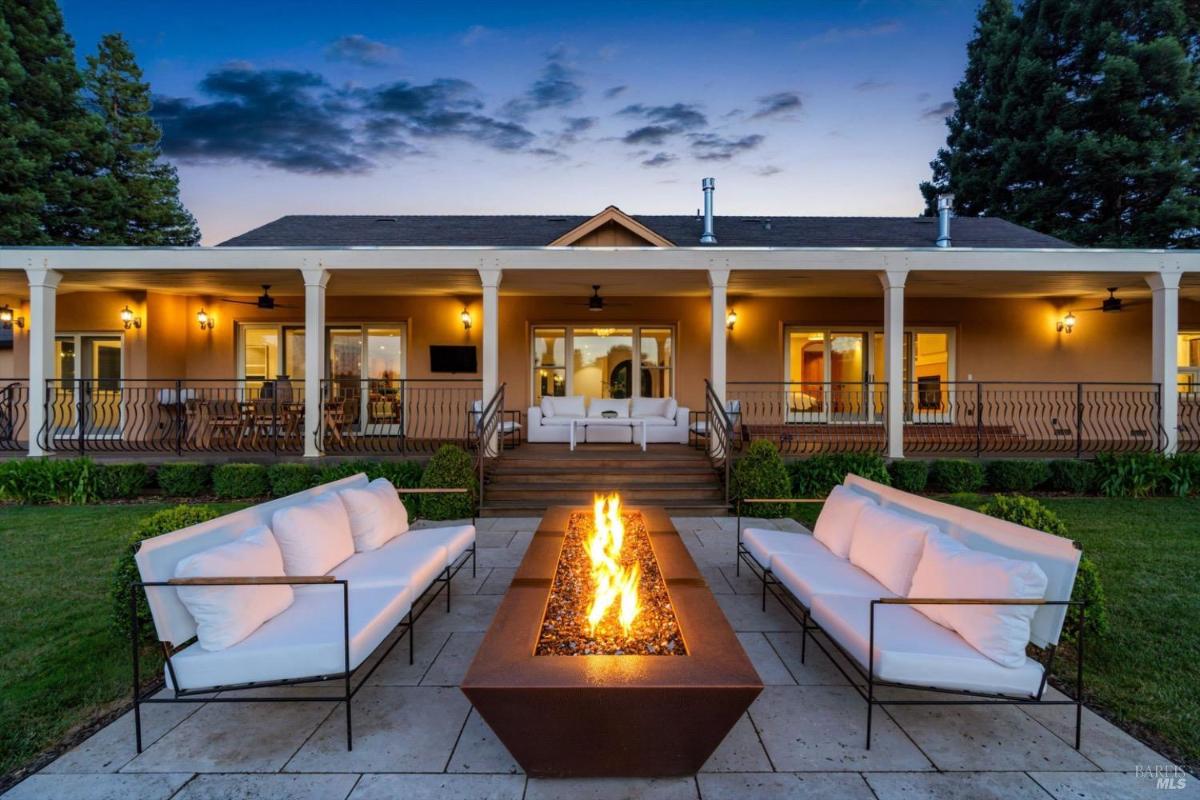 Evening view of a fire pit area with outdoor seating and a porch in the background.