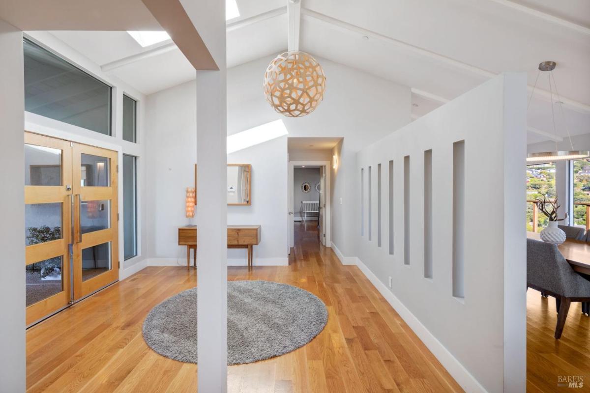 An foyer with hardwood floors, a round rug, and a decorative hanging light fixture.
