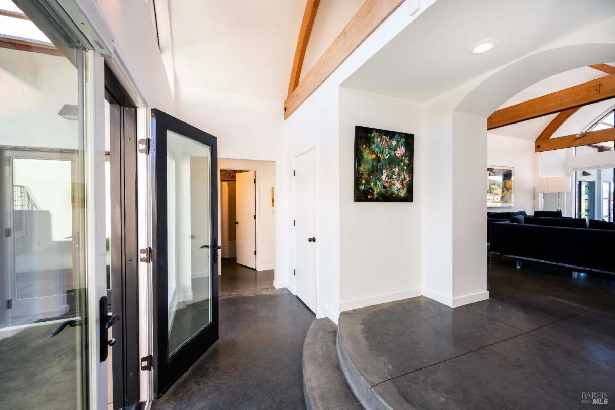A foyer featuring high ceilings with wooden beams, sleek flooring, and contemporary decor.