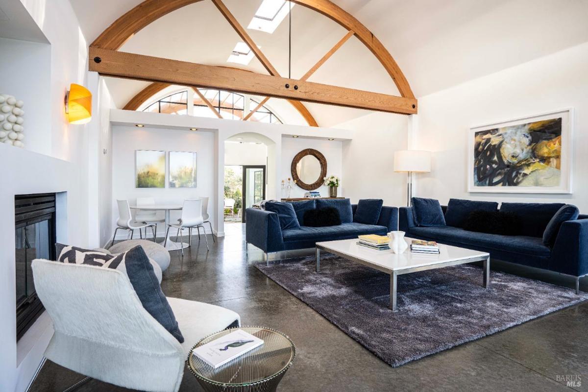 A modern living room with a large blue sofa, a coffee table, and a dining area in the background.