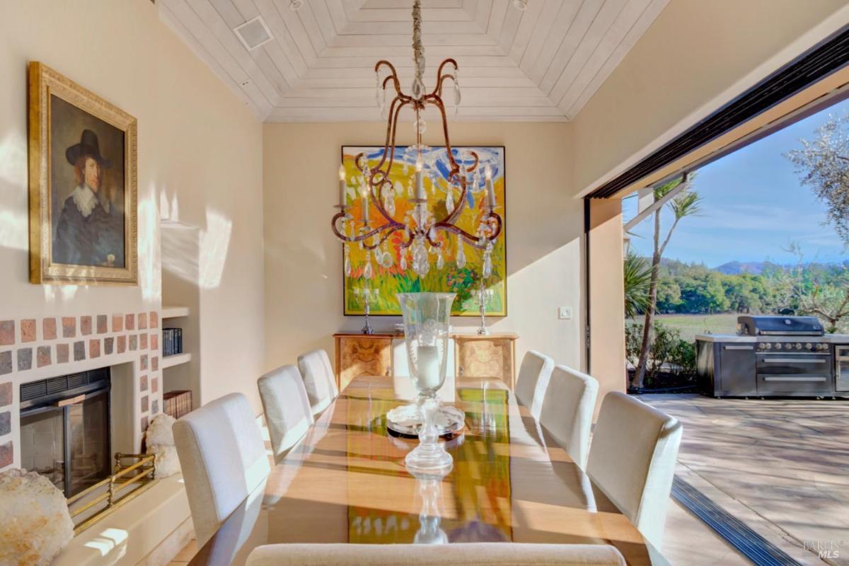 Dining room with a large table, chandelier, and sliding doors leading to an outdoor area.