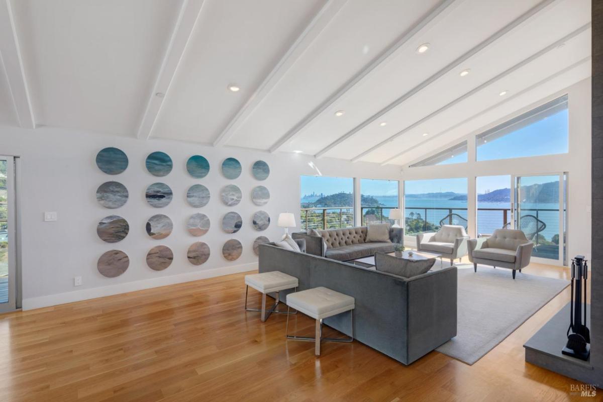 A living room featuring wall art, hardwood floors, and expansive windows overlooking a water view.
