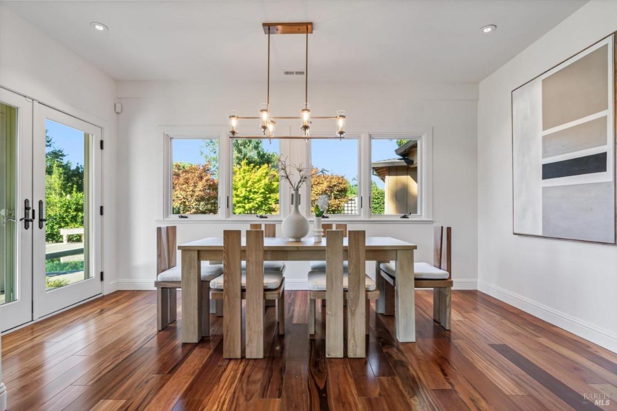 Dining area with a wooden table, chairs, and large windows.