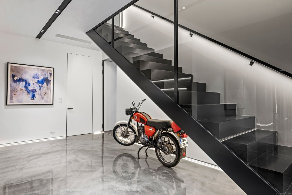 An interior space with a dramatic black open-concept staircase with glass railing dominating the composition.