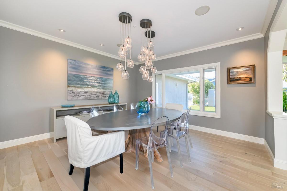 Dining room with a large table, chandelier, and window overlooking the yard.