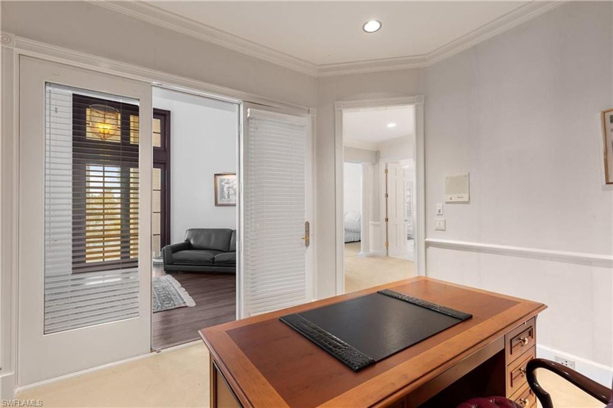 A view from the home office highlights its seamless access to adjacent living spaces through elegant French doors with integrated blinds.