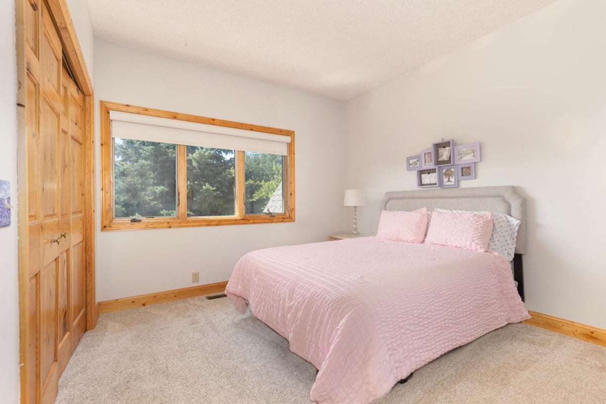 Bedroom is simply decorated with a light pink comforter on a bed with a gray headboard.