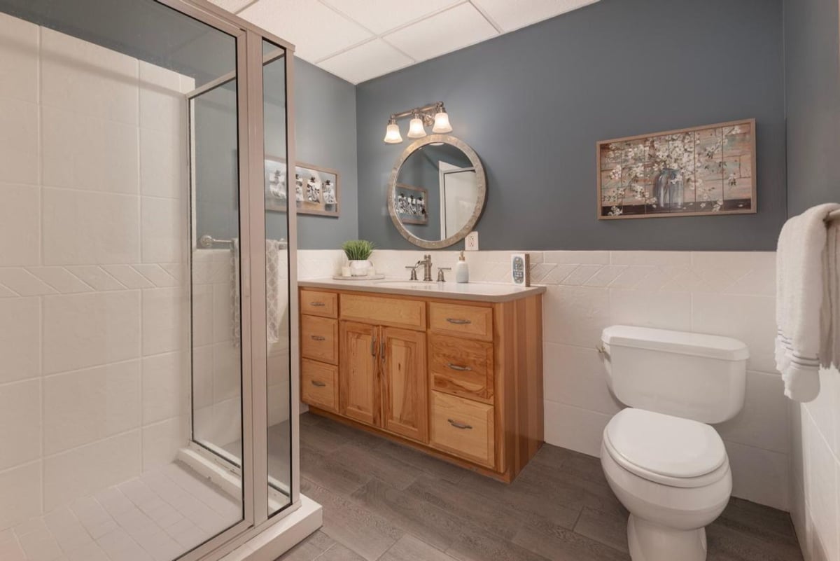 Dark walls, light wood vanity, and a walk-in shower comprise a modern bathroom.