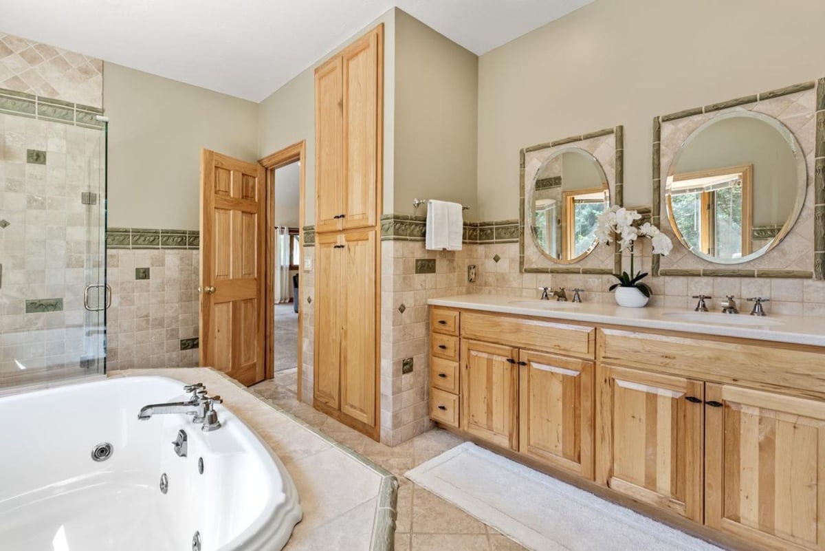 Double sinks, a large soaking tub, and wood cabinetry create an elegant master bathroom.