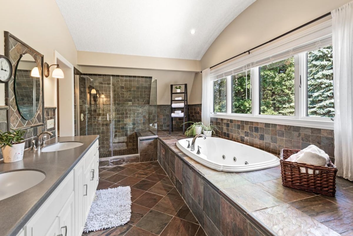 Dark tile, a large soaking tub, and double vanities define this elegant bathroom.