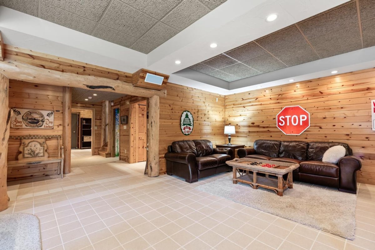 Wood-paneled walls, a large leather couch, and a stop sign create a rustic living area.