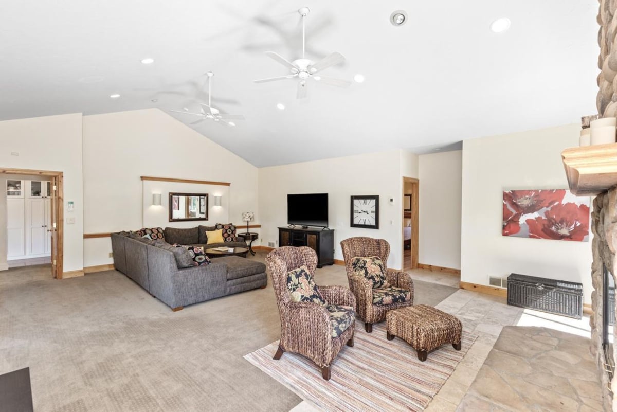Vaulted ceilings, two ceiling fans, and a large sectional sofa create a relaxing atmosphere in this open-plan living area.