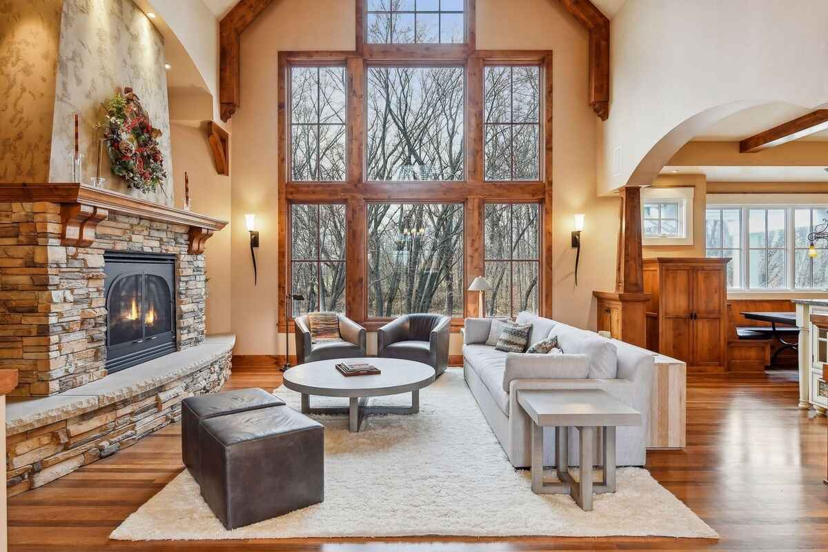 The living room features a stone fireplace, tall windows, and hardwood flooring.