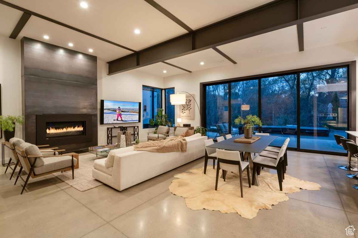 A modern living room with a sleek fireplace, large windows, and open dining space.