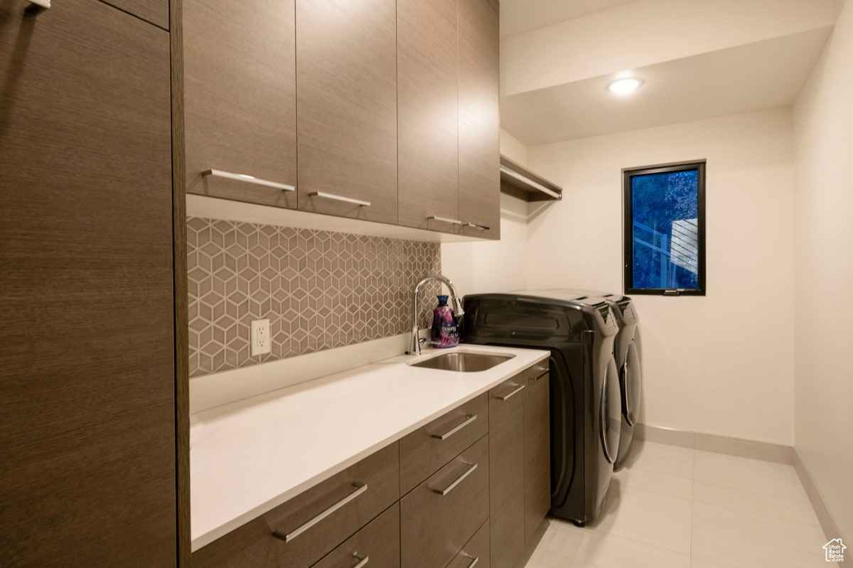 A functional laundry room with modern cabinetry, a sink, and a washer/dryer unit.