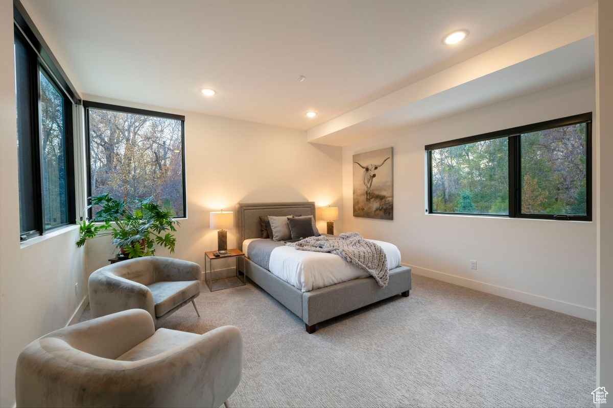 A cozy bedroom with large windows and neutral decor.