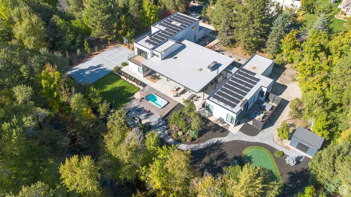 A modern home with a flat roof and large patio area, surrounded by snowy landscaping and trees.
