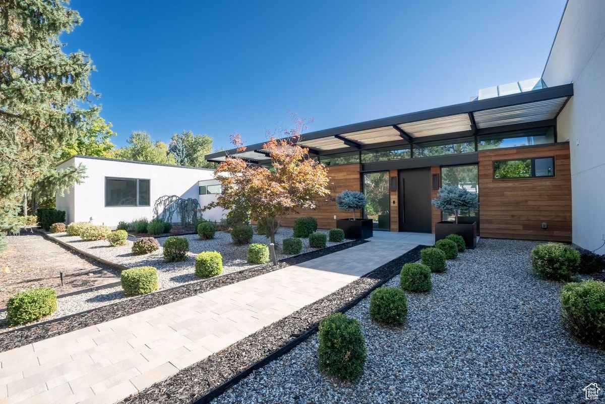 A closer look at the front door of the modern home, flanked by symmetrical planters with trees.