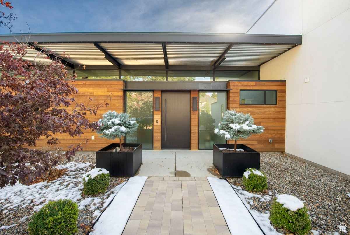 A snowy backyard view showcasing a sleek patio area and landscaping.