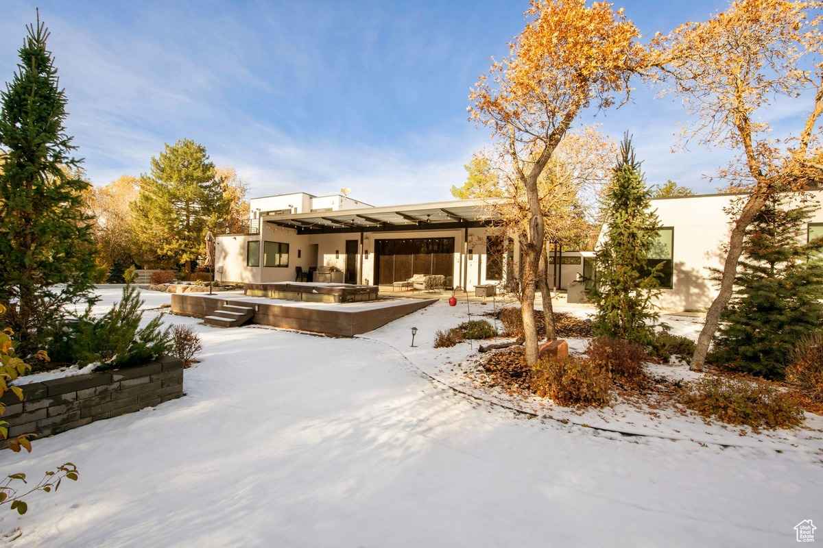 A snowy backyard view showcasing a sleek patio area and landscaping.