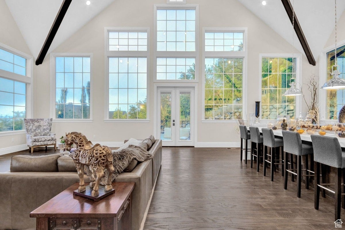 From a slightly angled perspective, this photograph captures the grandeur of a living area designed for both comfort and entertaining. The image emphasizes the dramatic use of natural light, highlighting the high ceilings and the elegant furnishings against the backdrop of the expansive windows.
