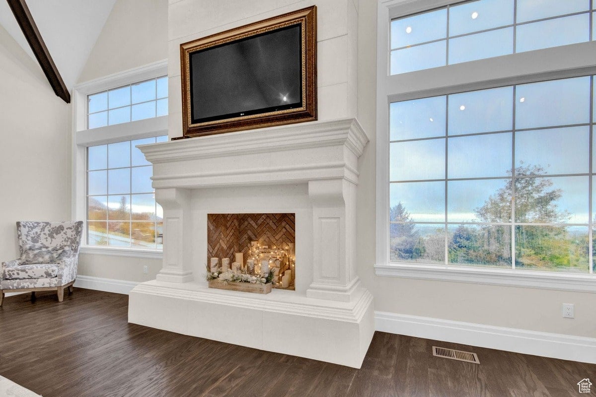 This wide-angle shot captures a portion of a living room, highlighting the elegant fireplace with its integrated television and the large windows providing abundant natural light. The overall aesthetic is one of refined simplicity and modern luxury. You sent 