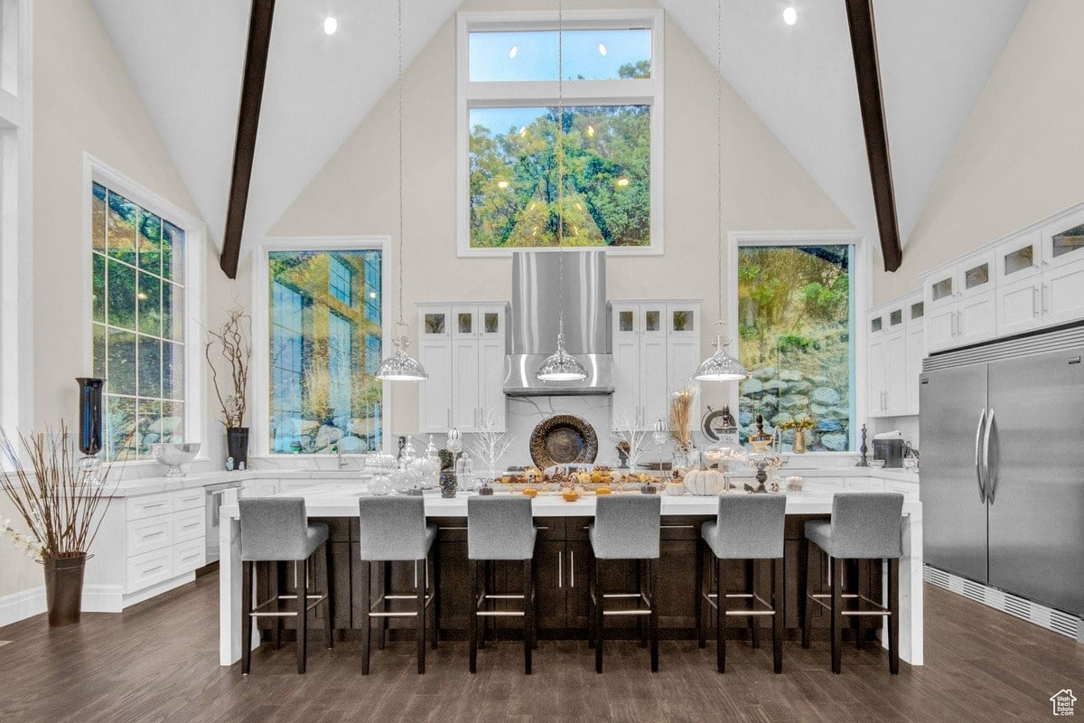Dominated by a large central island and floor-to-ceiling windows, this modern kitchen offers a bright and airy atmosphere. The high ceilings and exposed beams add architectural interest to the space, creating a unique and stylish culinary hub.